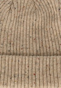 Gehaakte beanie in lichtbeige met een geribbeld patroon, met kleurrijke stippen in rood, oranje en zwart verspreid over de stof. Omgeslagen boord aan de onderkant.