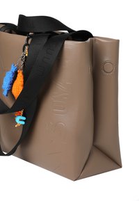 Bruine synthetische tote tas met een geperst logo, zwarte band en kleurrijke bedelaccenten. Gladde textuur; rechthoekige vorm met afgeronde hoeken.