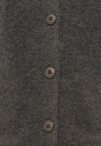 Γκρι μάλλινο ζακέτα με υφή υφάσματος, πέντε κουμπιά σε σκούρο καφέ απόχρωση και απαλή, αφράτη όψη.