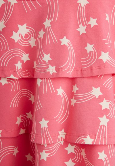 Ροζ ύφασμα με λευκά μοτίβα πεφταστεριών και λεπτομέρειες με στρώσεις βολάν σε κοντινή όψη.