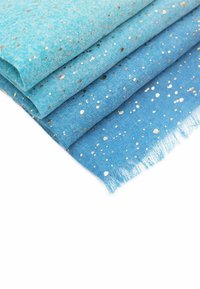 Tre tessuti piegati in diverse tonalità di blu, caratterizzati da un motivo a macchie con accenti metallici dorati e un bordo sfilacciato sul pezzo inferiore.