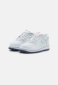 Ett par ljusgrå låga Nike Air Force 1 sneakers med vita mellansulor, marinblå yttersulor och orange logotypdetaljer.