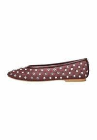 Zapato plano burdeos con punta redonda, adornado con remaches plateados en la parte superior, con una suela de goma marrón clara y baja.