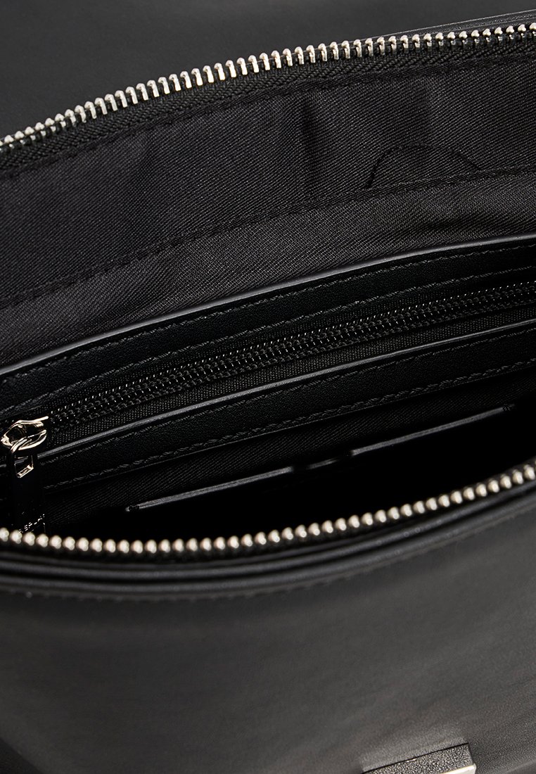 Interno di una borsa nera, con una fodera in tessuto liscio. Include una tasca con zip e cuciture a contrasto lungo le cuciture.