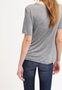 Gray short-sleeve t-shirt with a relaxed fit, smooth texture, and a crew neckline, paired with dark blue fitted jeans.