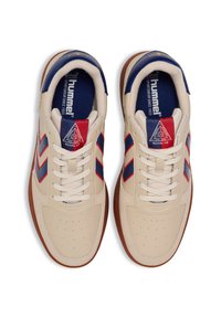 Scarpe da ginnastica beige con strisce blu e rosse. Presentano una tomaia in pelle, una zona delle dita perforata e una suola in gomma naturale. Design con lacci.