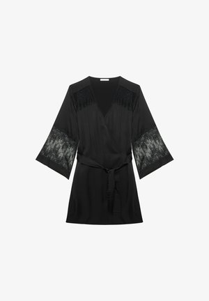 Black satin wrap dress with sheer floral lace panels on shoulders and wide sleeves, tied belt at waist, knee-length.