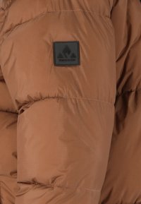 Brun nylon puffer-jakke med quiltet design, der har et tekstureret logo-patch og elastiske manchetter for en sikker pasform.