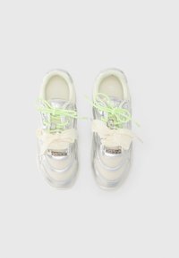 Ασημένια και εκρού αθλητικά παπούτσια με υφές από διχτυωτό ύφασμα και δέρμα, κορδόνια νέον πράσινου χρώματος, κορδέλες για δέσιμο και μικρή διακοσμητική λεπτομέρεια με λογότυπο στο πλάι.