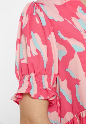 Mâneci scurte bufante cu model abstract roz, albastru și roz deschis, manșetă elastică și tiv cu volănașe pe o bluză din material texturat.