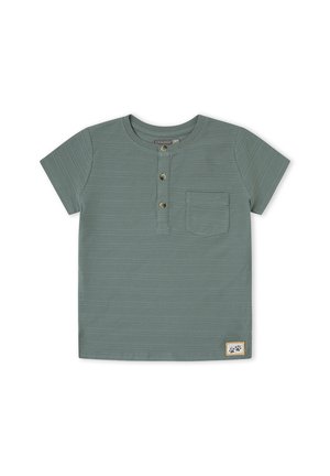 Camisa henley de manga corta en verde con tres botones frontales, un bolsillo en el pecho, una textura horizontal sutil y un pequeño parche con logo en el dobladillo.