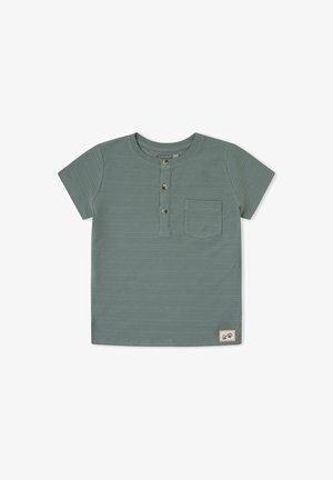 Camisa henley de manga corta en verde con tres botones frontales, un bolsillo en el pecho, una textura horizontal sutil y un pequeño parche con logo en el dobladillo.
