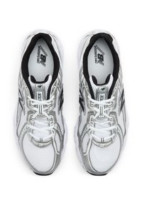 Paire de chaussures de course New Balance blanches et argentées avec doublure intérieure noire et lacets blancs vues de dessus sur fond blanc.
