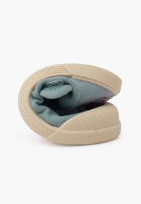 Helleblaue Stoffschuhe mit runder Form, beige Gummisohle, strukturierten Details und in gefalteter Position, die das weiche Innenfutter zeigt.