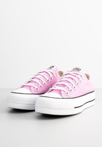 Rosa canvas låga sneakers med vita gummisålar, svarta detaljer och silverfärgade öglor. Har en rund tå och en strukturerad ovandel.