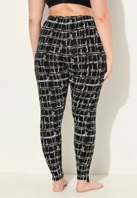 Leggings à motifs noir et blanc avec un design en damier, taille haute avec une texture lisse, ajustées aux jambes, se terminant juste au-dessus des chevilles.