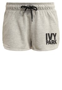 Pantalones cortos de felpa gris claro con cinturilla elástica y cordón negro, que presentan el logo "IVY PARK" en letras negras en negrita en la pierna izquierda.