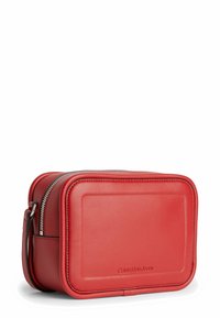 Bolso bandolera de cuero rojo con forma rectangular, cierre de cremallera y logo grabado. Presenta una textura suave y una correa ajustable.