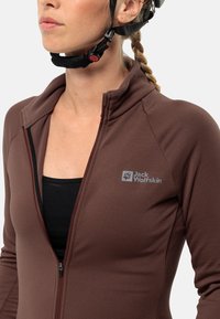 Giacca marrone con zip e colletto alto, realizzata in tessuto liscio, con un piccolo logo sulla parte sinistra del petto.