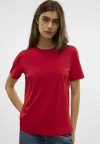 Rode T-shirt met korte mouwen, gemaakt van gladde, elastische stof. Voorzien van een ronde halslijn en een relaxte pasvorm, gecombineerd met blauwe denim shorts.