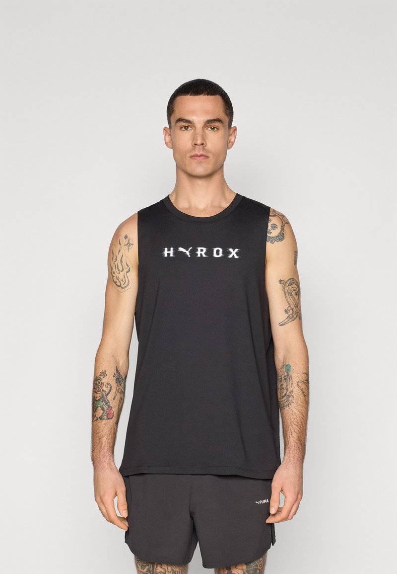 Zwarte mouwloze sport tanktop met een ronde hals en een wit "HYROX" logo op de borst; gedragen met bijpassende shorts.