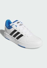 Bijela atletska cipela s crnim trakama, plavim naglascima i teksturiranim prstom. Ima vezanje na vezice i podstavljeni ovratnik za udobnost.