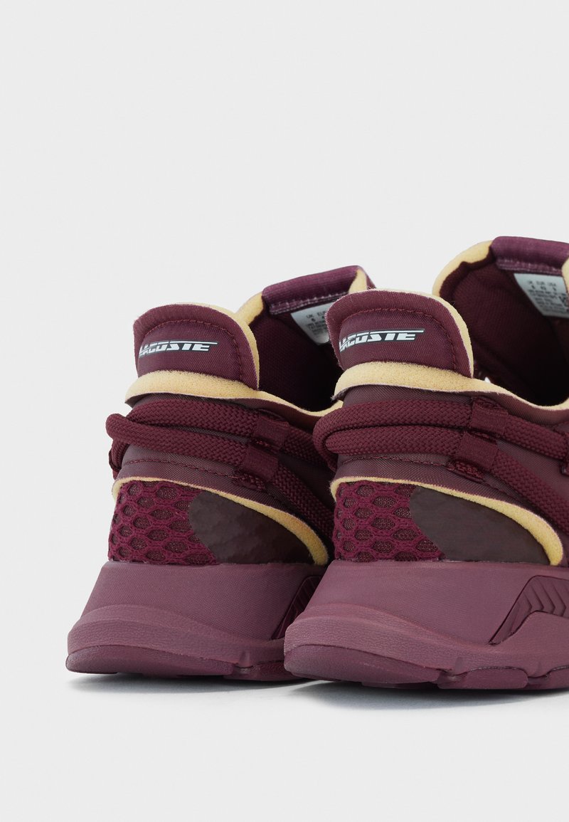 Scarpe da ginnastica bordò con superiore in rete testurizzata, colletto imbottito e suola in gomma. Presentano accenti scanalati e un interno giallo a contrasto.