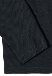 Gros plan d'un tissu côtelé noir montrant une manche longue pliée et les détails de la couture de l'ourlet.