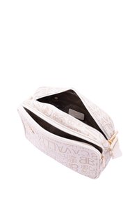 Borsa in tessuto bianco con motivo del logo dorato, chiusura con zip e interno marrone. Presenta una forma rettangolare e una tracolla con dettagli in hardware dorato.