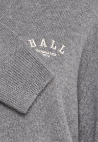 Suéter gris de punto con cuello acanalado. Presenta texto bordado "BALL" y "ORIGINADO 1974" en blanco. Textura suave y diseño clásico.