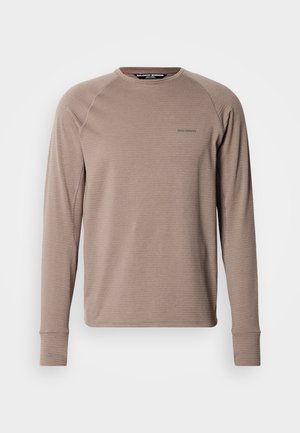 Majica z dolgimi rokavi svetlo rjave barve z rebrasto teksturo in kontrastnimi šivi. Ima okrogel izrez in majhen logotip na prsih.