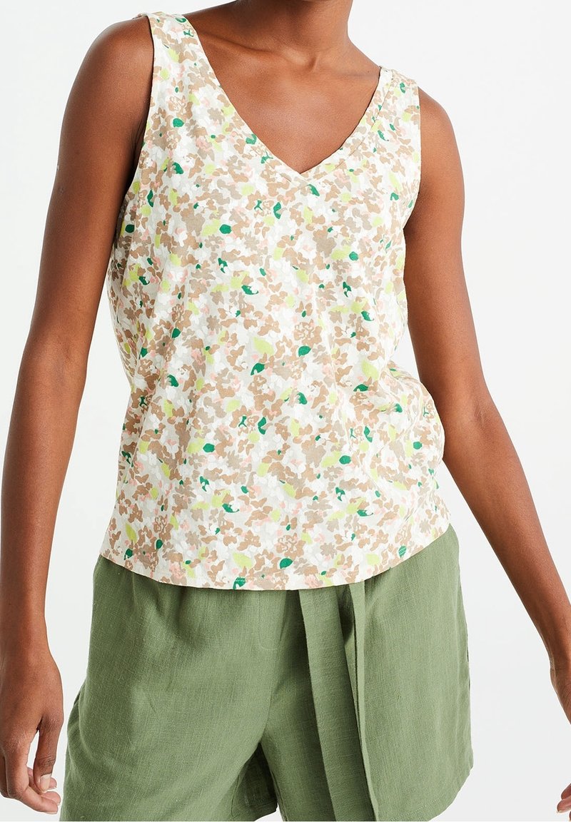 Débardeur à imprimé floral dans des tons pastel beige, vert et blanc. Doté d'un décolleté en V et de larges bretelles, fabriqué en tissu léger.