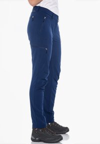 Dunkelblaue Outdoor-Hosen aus leichtem Material; mit mehreren Reißverschlusstaschen, schmalem Schnitt und belüftetem Design.