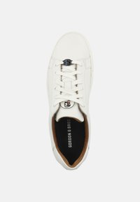 Sneaker bianco in pelle con punta arrotondata, chiusura lacci, logo nero e rosso sulla linguetta, colletto imbottito e fodera interna marrone.