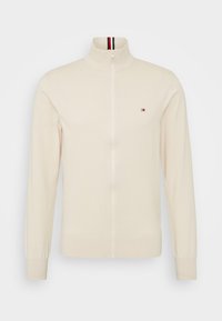 Maglione crema con cerniera, collo, polsini e orlo a coste, con piccolo logo rosso, bianco e blu navy sul petto e dettaglio a righe all'interno del collo.