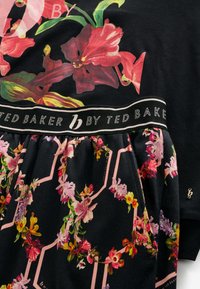 Virágmintás pamutkeverék felső fekete alappal, élénk rózsaszín és zöld virágmintákkal; rugalmas derékrész logóval díszítve; selymes tapintású.