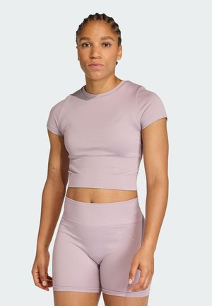 Vaaleanvioletti urheilullinen lyhyt toppi ja korkeat shortsit, jotka on valmistettu sileästä, joustavasta kankaasta. Varustettu lyhyillä hihoilla ja hillityllä brändin logolla.