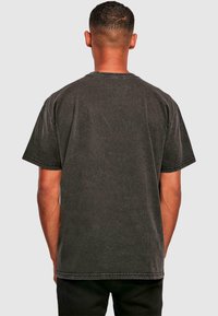 Sort T-shirt med korte ærmer, der har en rund halsudskæring, lige søm og synlige sømdetaljer, lavet af blødt, tekstureret bomuldsstof.