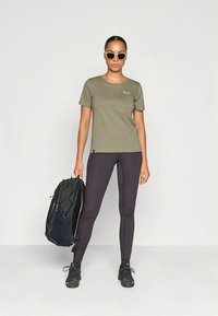 Olive roheline puuvillane T-särk ümara kaelusega, koosmustritega mustad retuusid. Komplektis on must seljakott.