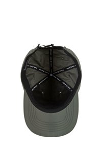 Căciulă verde cu o închidere neagră, dotată cu orificii de ventilație și o bandă interioară etichetată cu "KARL KANI." Textură netedă, design structurat.