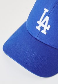 Blaues Baseballcap aus strukturiertem Stoff, mit einem auffälligen weißen "LA"-Logo, das auf der Vorderseite gestickt ist. Mit gebogenem Schirmdesign.