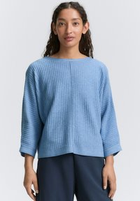 Maglione azzurro chiaro in tessuto strutturato con maniche a tre quarti e vestibilità rilassata. Presenta una cucitura orizzontale al centro e polsini a coste.