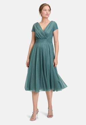 Abito in tulle verde con scollatura a V e maniche corte, caratterizzato da una vita aderente e una gonna fluida decorata con dettagli di lucentezza sottile.