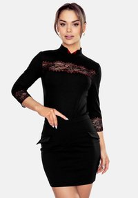 Czarna sukienka bodycon z koronkowym panelem na klatce piersiowej i rękawach, z kołnierzykiem mandaryńskim i falbankami przy spódnicy.