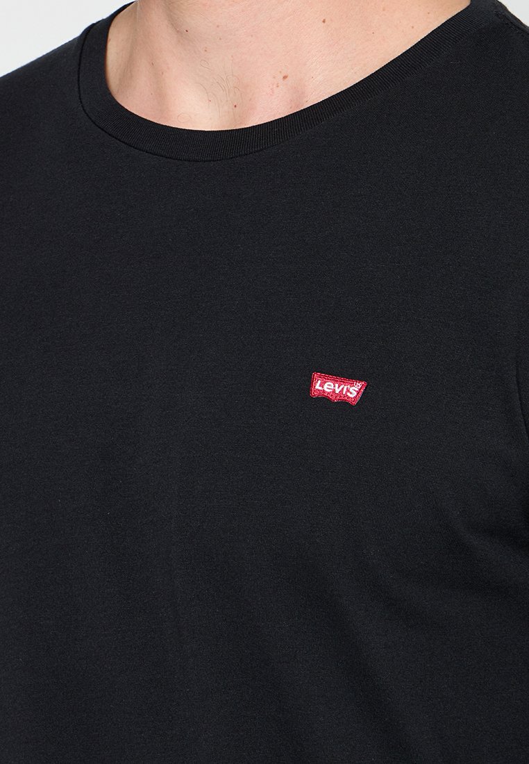 Camiseta negra de manga corta de algodón, con cuello redondo y un pequeño parche del logo rojo de Levi's en el pecho izquierdo.