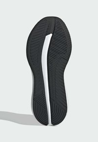 Black rubber shoe sole with a textured, tread pattern and a white midsole stripe. Rounded shape with curved edges and distinct grooves.