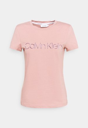 Lyserød t-shirt med korte ærmer med "Calvin Klein" trykt i lilla henover brystet og rund halsudskæring.
