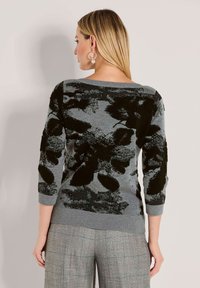 Grauer Pullover mit schwarzem Blumenmuster, ausgestattet mit einem Bootsausschnitt und 3/4-langen Ärmeln. Weicher Stoff mit gerippten Bündchen und Saumdetails.