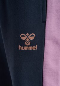 Marinblå och rosa sweatpants med en strukturerad yta, som har en metallisk roséguld "hummel"-logotyp och dekorativ sömdetalj.