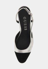 Scarpa slingback metallica argento con punta in suede nera. Caratterizzata da una cintura regolabile e un'insole nera a contrasto con il logo del marchio.
